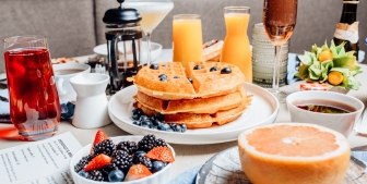 A weekend brunch served at The Gwen with a stack of blueberry waffles, fresh fruit and mimosas.