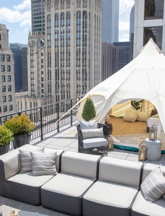 A tent setup for glamping on a balcony with a Chicago buildings in the background