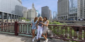 A group of ladies taking a picture on a foot bridge above the Chicago river.