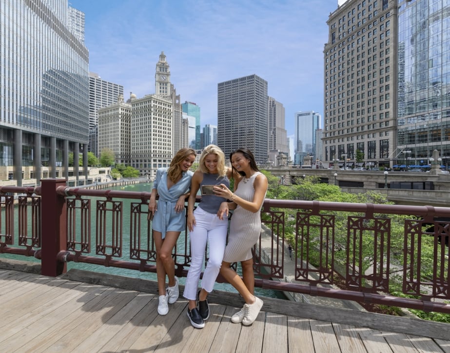 A group of ladies taking a picture on a foot bridge above the Chicago river.