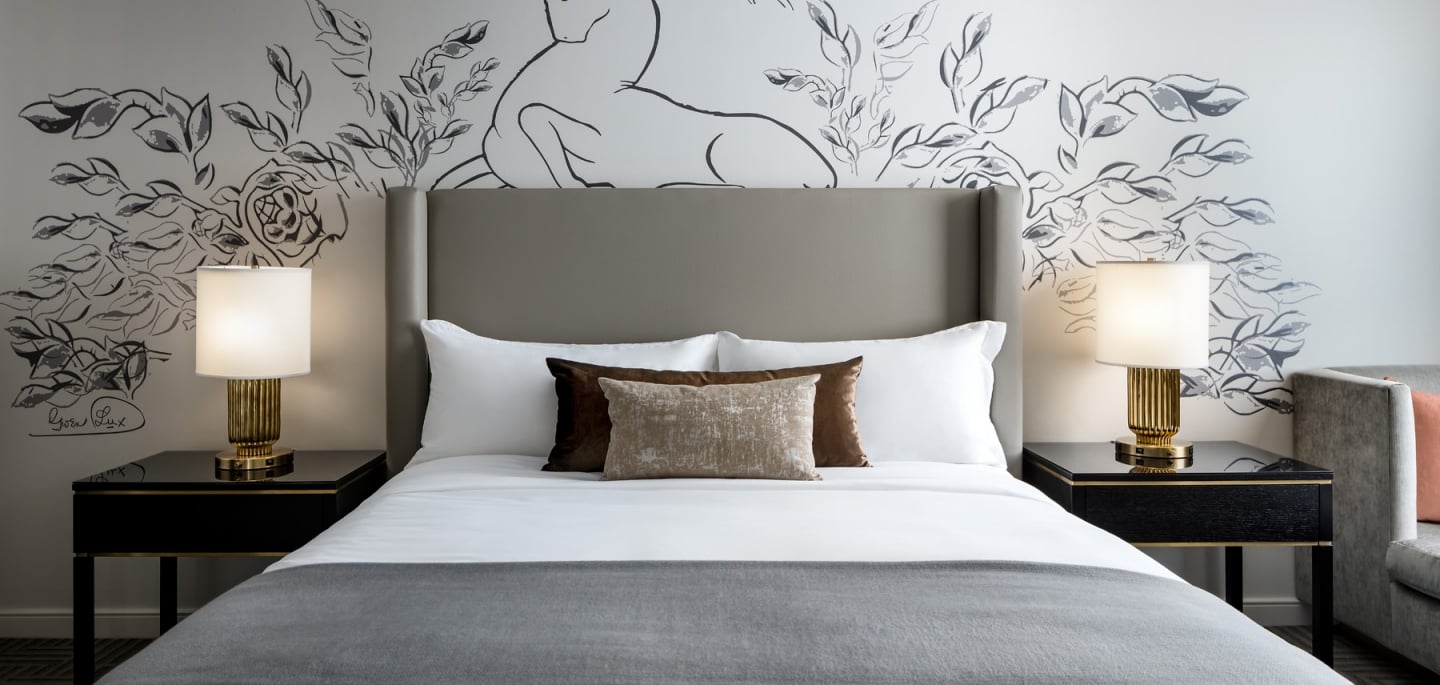 Straight on view of a bed and side tables with artwork on the wall