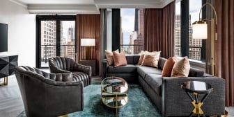 A sectional couch and two leather chairs in a hotel room.