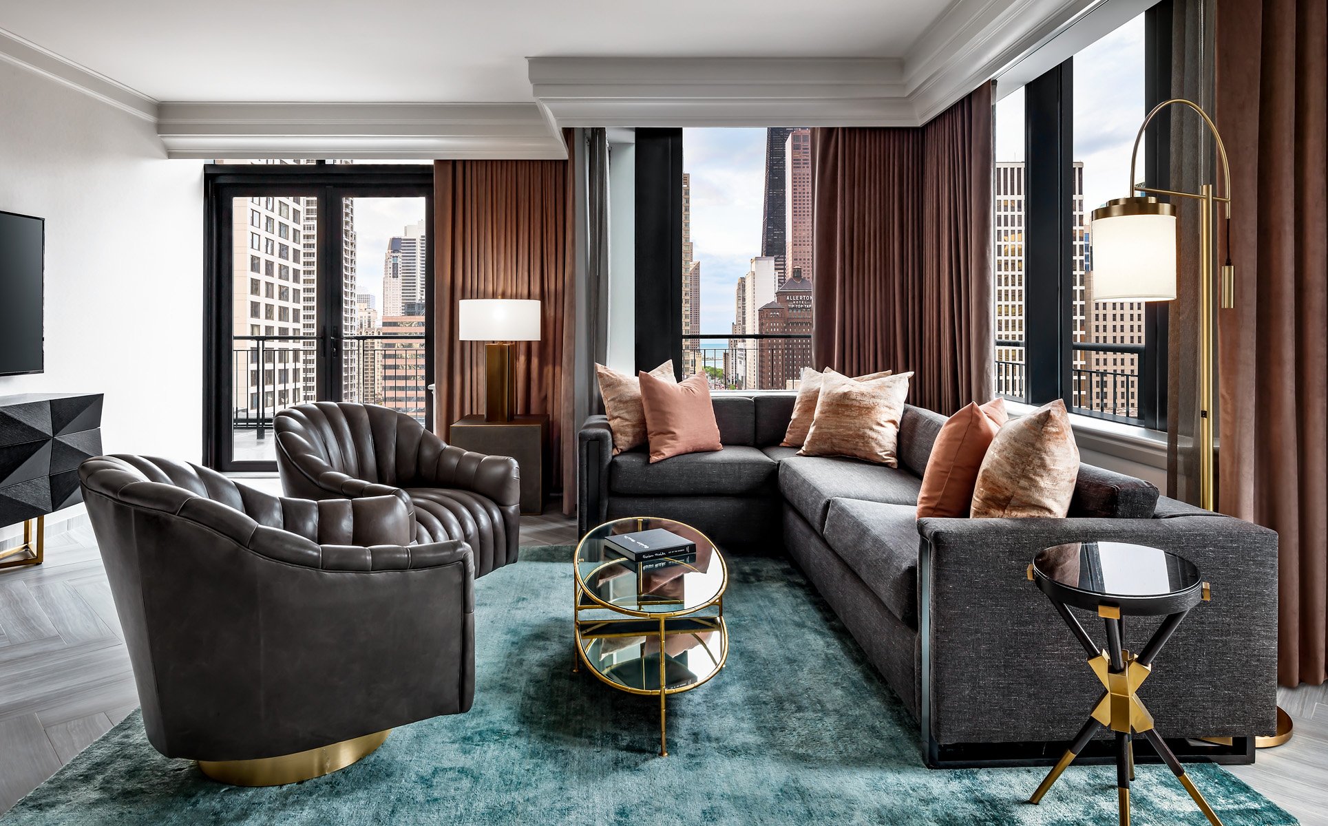A sectional couch and two leather chairs in a hotel room.