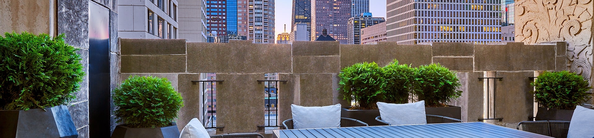 A balcony with a large outdoor table and views of downtown Chicago.