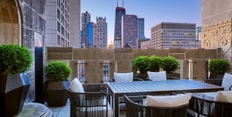 A balcony with a large outdoor table and views of downtown Chicago.