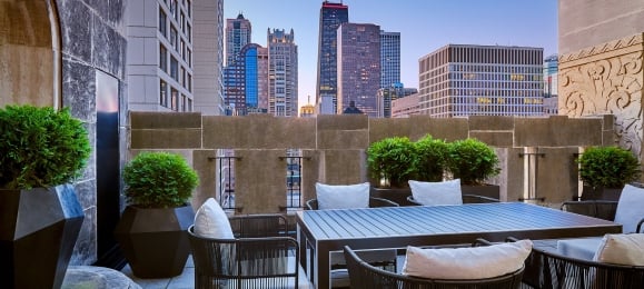 A balcony with a large outdoor table and views of downtown Chicago.