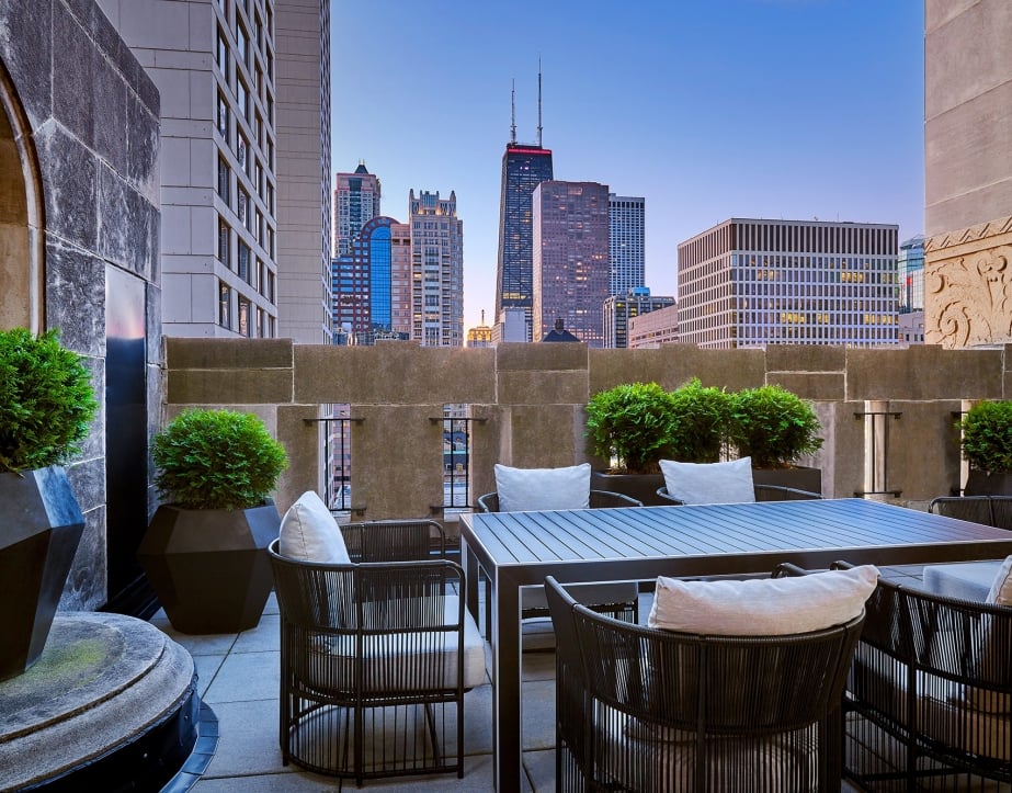 A balcony with a large outdoor table and views of downtown Chicago.