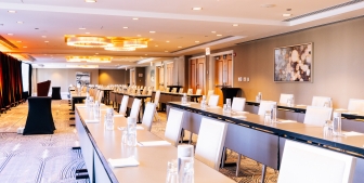 A conference room with rows of tables, chairs and a podium at the front.