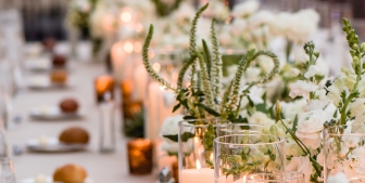 Rows of artisan bread, plates and candles laid out on the head table of an outdoor wedding at The Gwen.