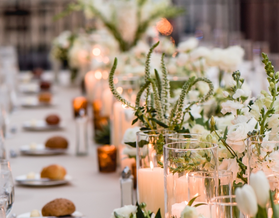 Rows of artisan bread, plates and candles laid out on the head table of an outdoor wedding at The Gwen.