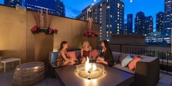 A group of friends enjoy evening drinks on the Upstairs at The Gwen's rooftop patio.