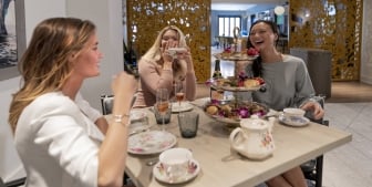 A group of ladies smiling and drinking tea.