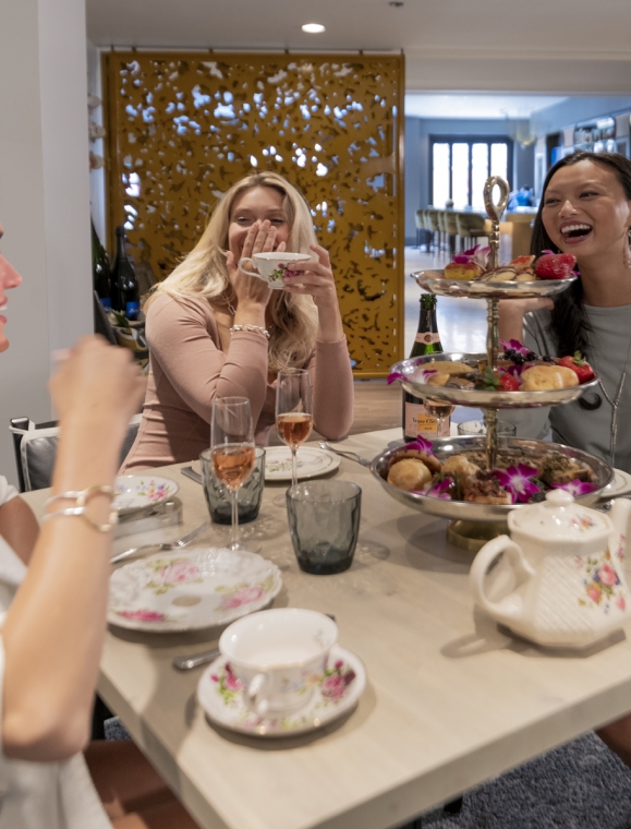 A group of ladies smiling and drinking tea.