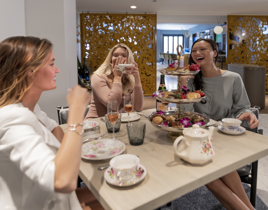 A group of ladies smiling and drinking tea.