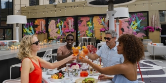 A group of friends cheers while enjoying drink on the rooftop patio at Upstairs at The Gwen.