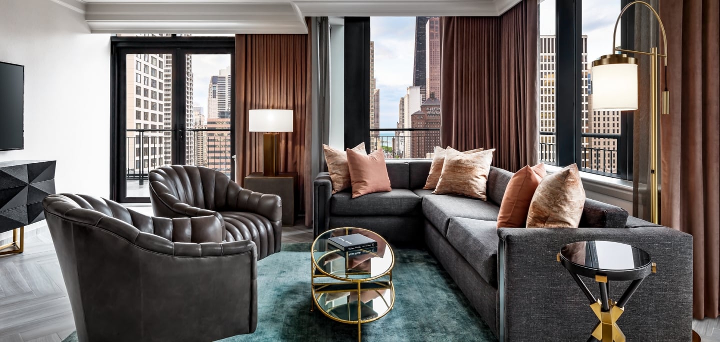 A sectional, two leather chairs and a green rug found in the Gwen Lux suite.
