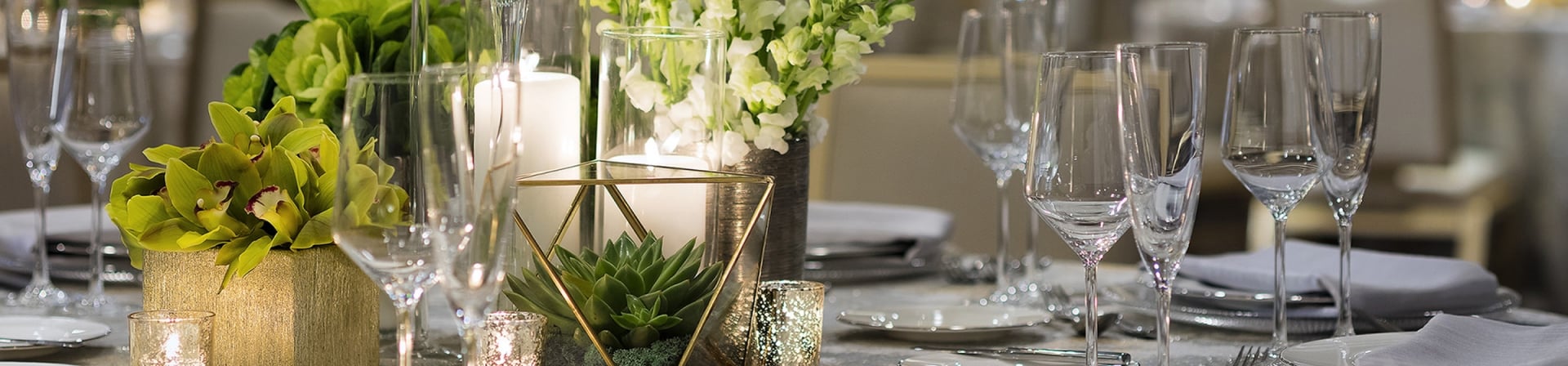 A table set for a wedding with candles, bouquets, and silver tableware.