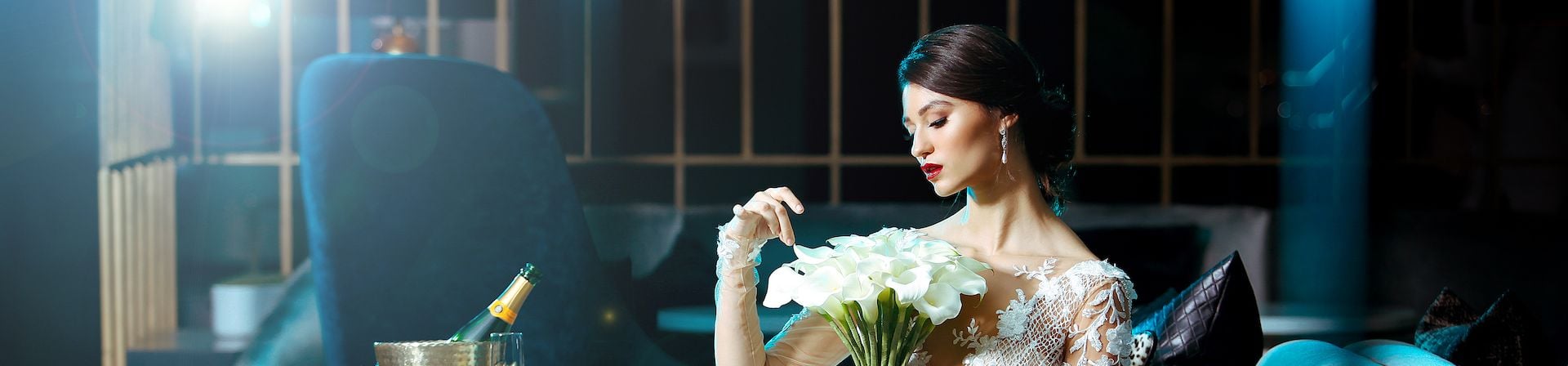 A bride dressed in a white gown and holding a bouquet of white roses.