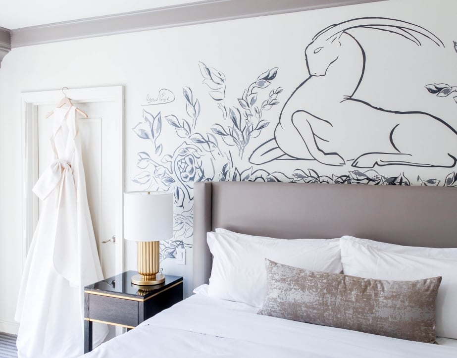A hotel room with a large king bed with white linens and wall art.